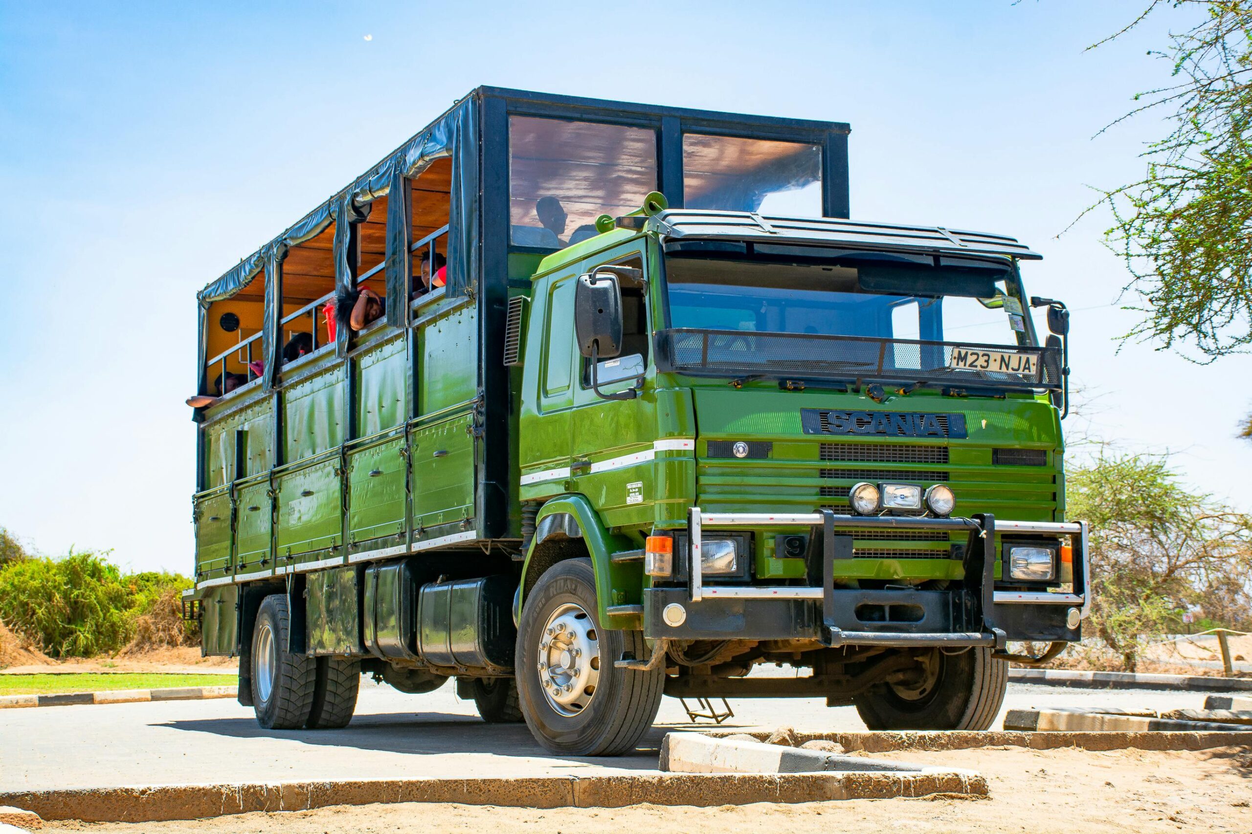 Green Scania truck parked outdoors in Namanga, Kenya, under a bright blue sky.